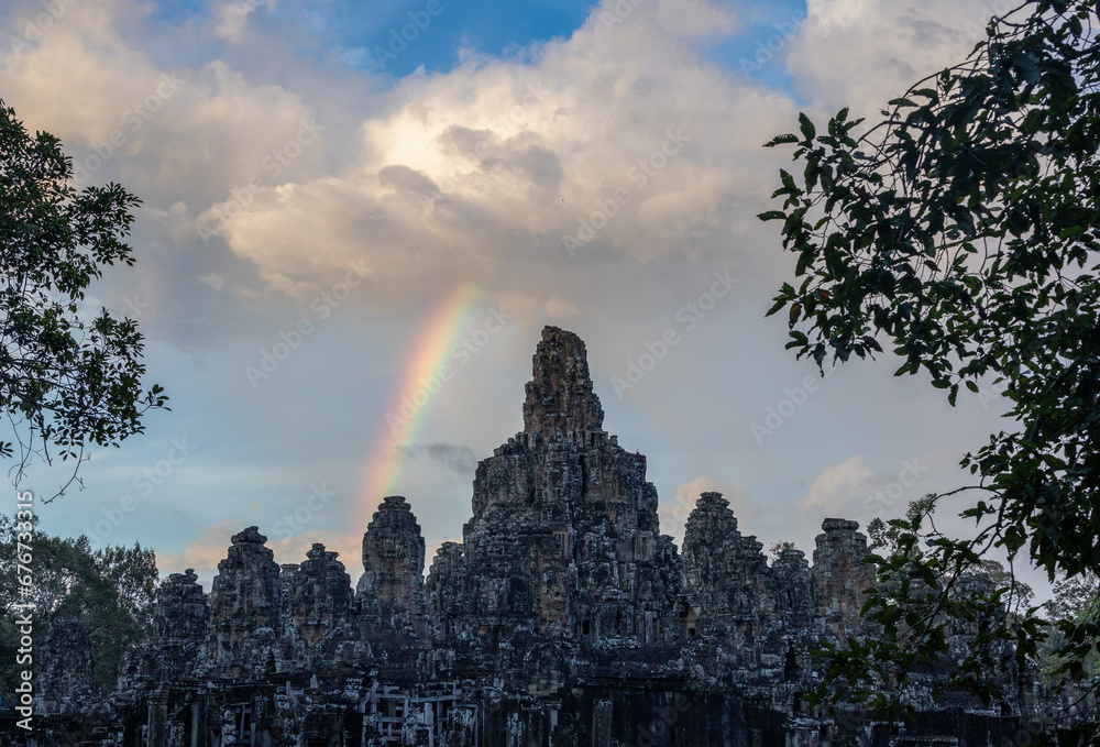Fototapeta premium As the sun sets. Bayon temple Angkor, Siem Reap, Cambodia in the late evening light. A rainbow is visible in the sky.