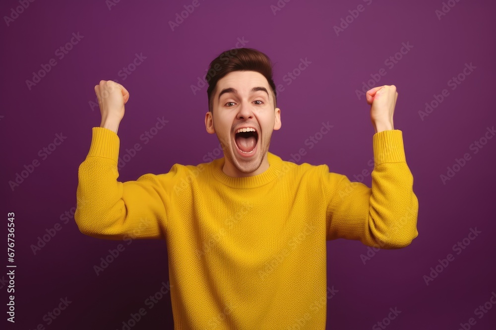 Fototapeta premium A young bearded man standing against a yellow background rejoicing in success and victory, clenching his fists in joy and happy to achieve his goal and tasks. Positive emotions. generative AI