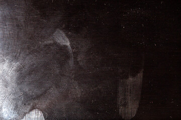 black surface with dust and oily fingerprints. full-frame close-up background