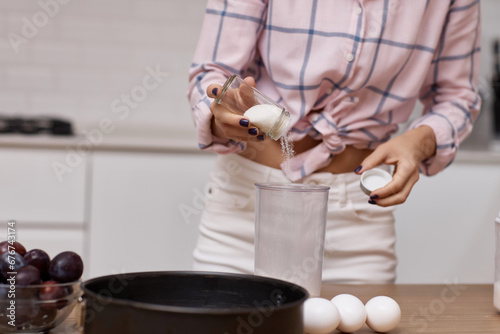 woman preparing pie in modern kitchen, adding ingredients to bowl