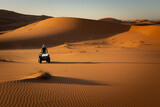 Berber nomad touring the Mezouga desert on a quad at dawn.