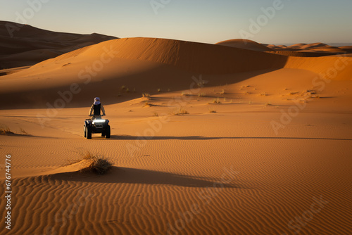 Berber nomad touring the Mezouga desert on a quad at dawn.