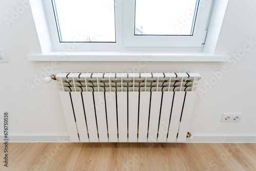 Wallpaper Mural The heating radiator hangs in the room under the window, the heating system in the house, the heating of cold air from the window. Torontodigital.ca