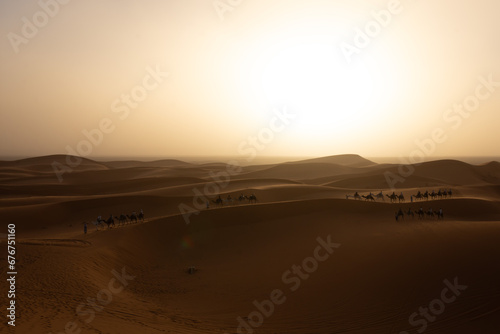 Fototapeta Naklejka Na Ścianę i Meble -  Mezouga Desert at sunset with tourists on dromedaries touring the sand dunes.