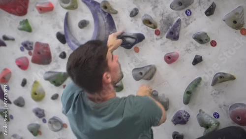 Man climbing slowly in bouldering mode in an indoor climbing gym. Active life and sporting activity.