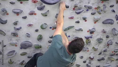 Young man climbing in an artificial indoor climbing wall with a fall. Active and healthy sporting life