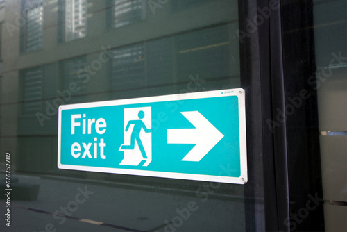 fire exit sign in blue on a glass building 