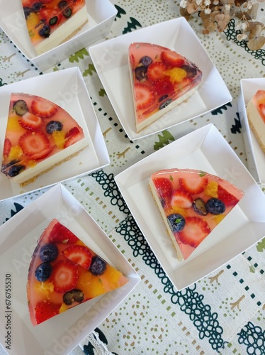 Jelly cheese pie with fresh fruit strawberry blueberry and orange sliced in triangle shape piece for cafe serving. Sweet and delicious cake in homemade bakery concept.