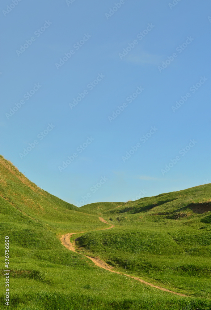 Landscape with a trampled path, passing through a wonderful green mountainous terrain. Photo of beautiful landscaped relief space with a thin path