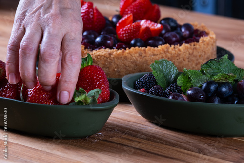 female hands decorating a berry pie with fruits