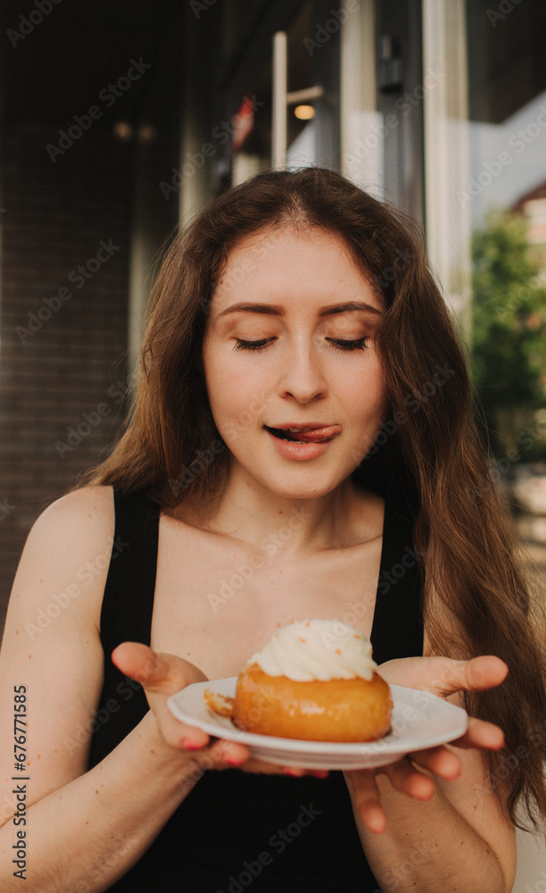 Portrait of a satisfied woman eating a cake while sitting at the table in a cafe indoors. Closeup of girl eating in a cafe. Selective focus, noise effect. Unhealthy eating concept Portrait of a satisfied woman eating a cake while sitting at the table in a cafe indoors. Closeup of girl eating in a cafe. Selective focus, noise effect. Unhealthy eating concept