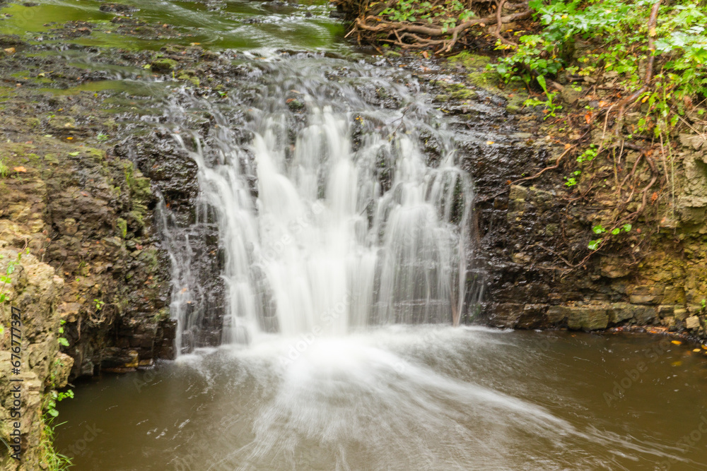 A small waterfall in the middle of the forest between dolomite rocks, long exposure A small waterfall in the middle of the forest between dolomite rocks, long exposure