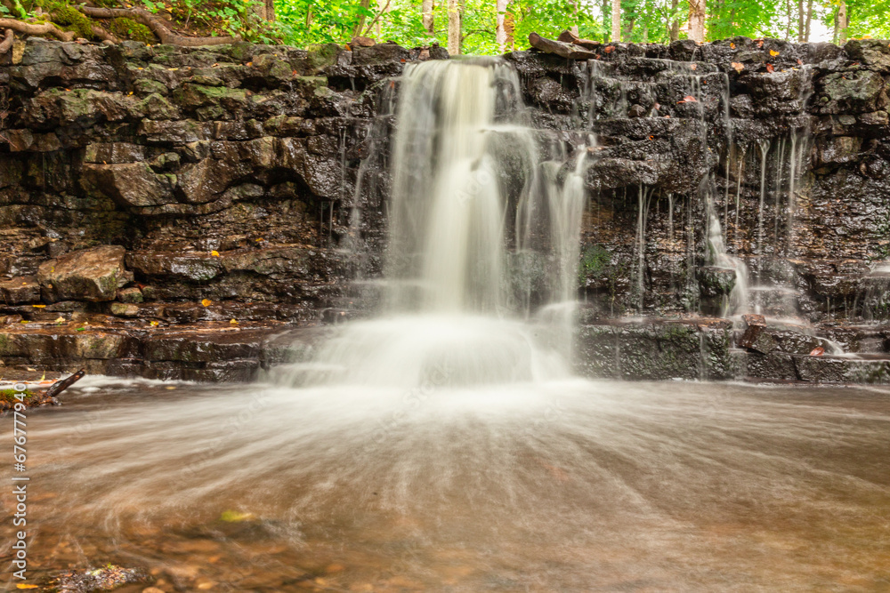Obraz premium A small waterfall in the middle of the forest between dolomite rocks, long exposure