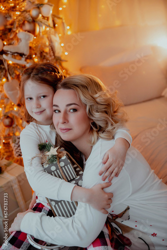 Mom and daughter hugging at christmas by the Christmas tree