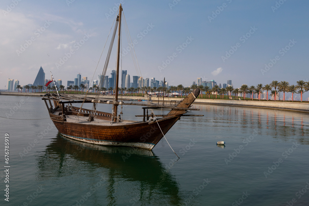 A view of the garden of the Museum of Islamic Art in Qatar, with the sea, boats and palm trees, with the Doha Towers as a background