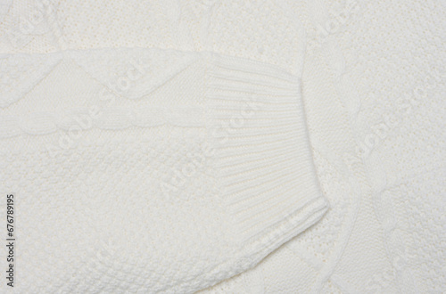 Fragment of a white knitted sweater, sleeve