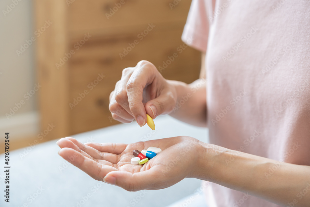 Sick ill asian young woman, girl hand taking tablet pill capsule out from blister pack, painkiller medicine from stomach pain, head ache, pain for treatment, take drug or vitamin at home, health care. - obrazy, fototapety, plakaty 