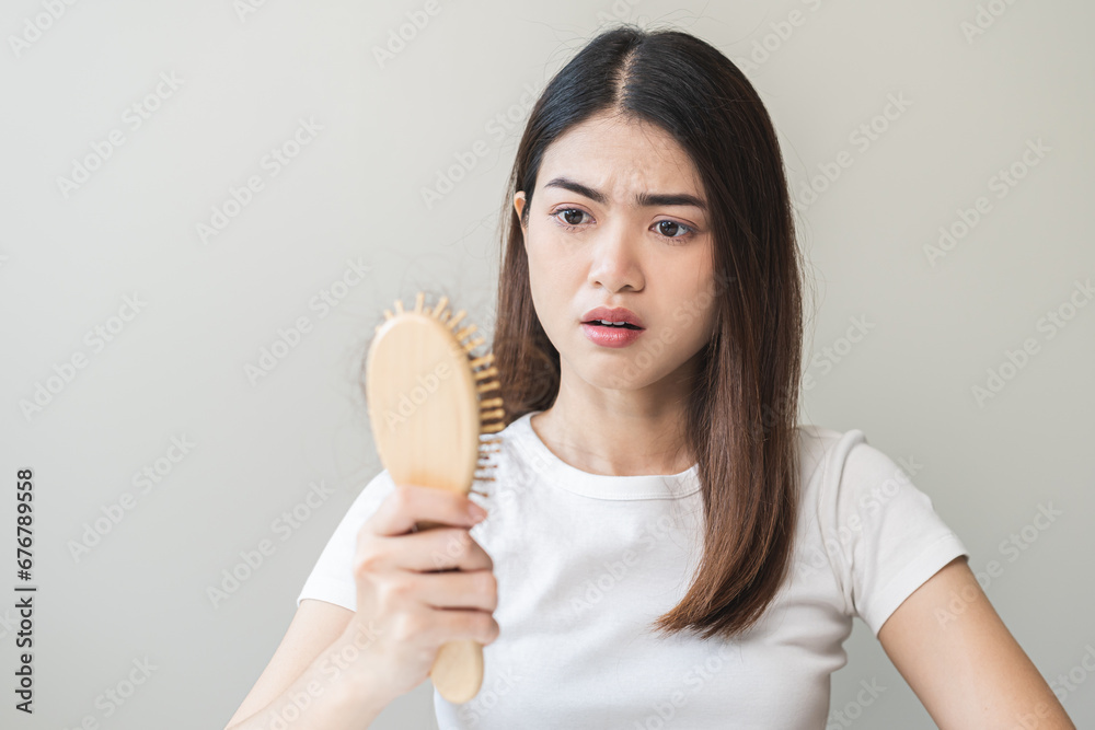 Serious asian young woman holding brush holding comb, hairbrush with fall black hair from scalp after brushing, looking on hand worry about balding. Health care, beauty treatment, hair loss problem. Serious asian young woman holding brush holding comb, hairbrush with fall black hair from scalp after brushing, looking on hand worry about balding. Health care, beauty treatment, hair loss problem.