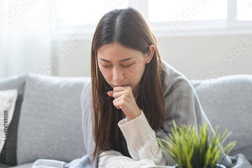 Sick, hurt or pain asian young woman, girl with sore throat, cough have a fever, flu and sneezing nose, runny sitting on sofa bed at home. Health care person on virus seasonal.