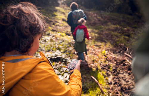 Back view boy using compass on family hike in nature photo