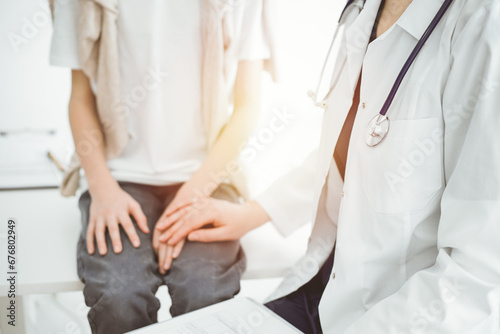 Doctor and child patient. The physician is holding clipboard and reassuring a boy. The concept of ideal health in medicine