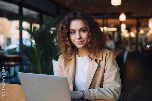 Attractive young lady immersed in her work on a laptop  a female freelancer or student engrossed with her computer at a cafe table  confidently gazing into the camera