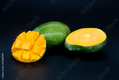 Fresh whole half and sliced mango fruit isolated on the black background