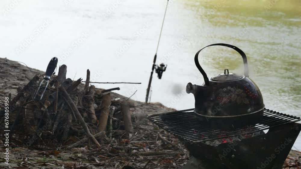 boiling teapot over burning ash, against the background of the river boiling teapot over burning ash, against the background of the river