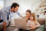 Happy family with little daughter having fun with laptop at home