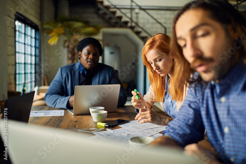 Diverse group of businesspeople discussing charts during meeting in modern office