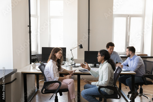 Pairs of busy multiethnic office colleagues talking at shared workplace table, collaborating on startup project, sharing ideas. HR, recruit managers interviewing job candidates in coworking © fizkes