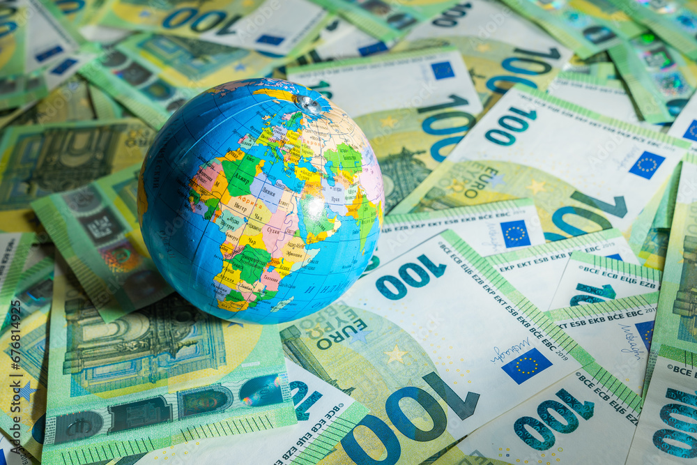 A globus over many money bills with background of 100 euros - obrazy, fototapety, plakaty 