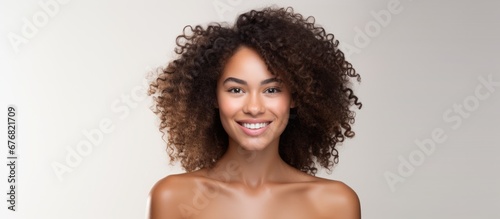 A woman with radiant skin and sexy hair wearing a smile on her face is seen in a portrait on a white background representing health beauty and the spa experience where people can feel isola