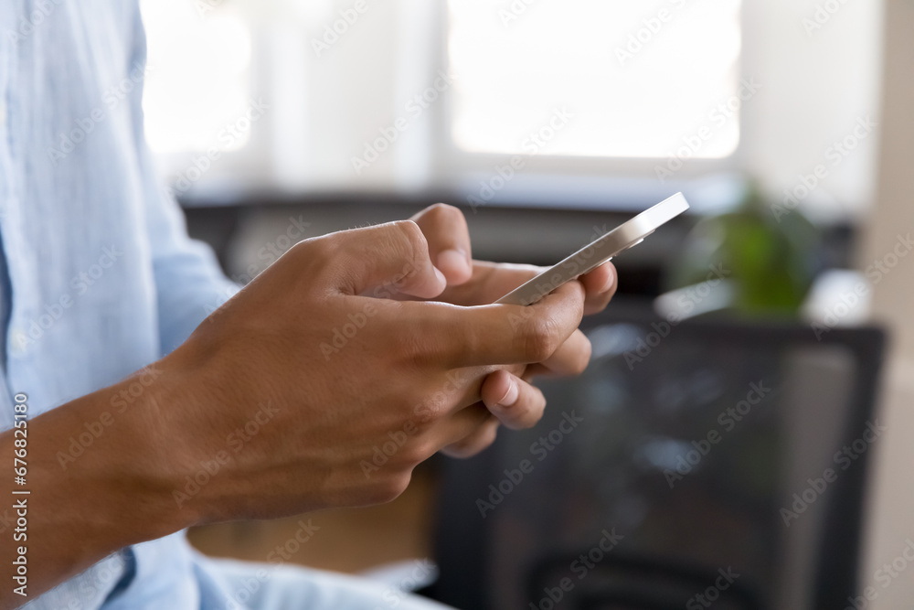 Close up of male human hands typing on mobile phone indoors. Young smartphone user man holding digital gadget, texting message on cellphone, chatting online, using app for Internet communication