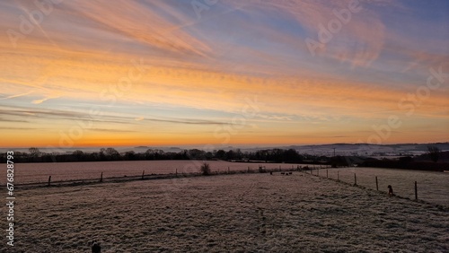 Shot of a fenced field under colorful cloudy dusk sky at sunset