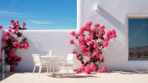 A minimalist Mediterranean White Wall, Accented by Delicate Pink Flowers. A pair of white chair and a table sitting on top of a white floor next to pink flowers. 