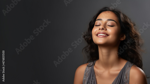 A Indian woman breathing calmly looking up isolated on gray background