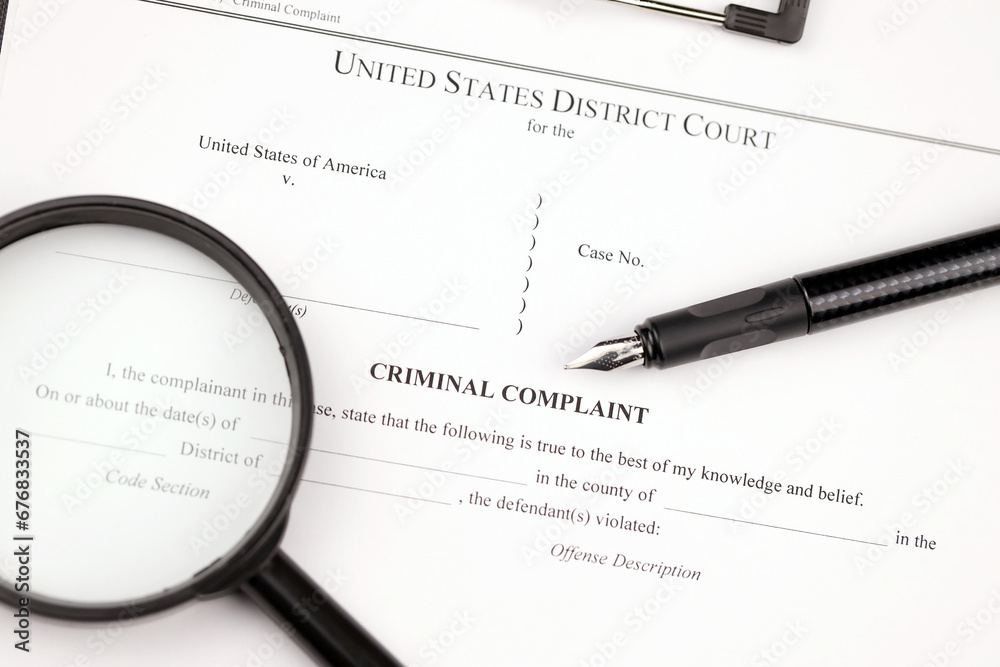 District Court Criminal complaint court papers on A4 tablet lies on office table with pen and magnifying glass close up District Court Criminal complaint court papers on A4 tablet lies on office table with pen and magnifying glass close up