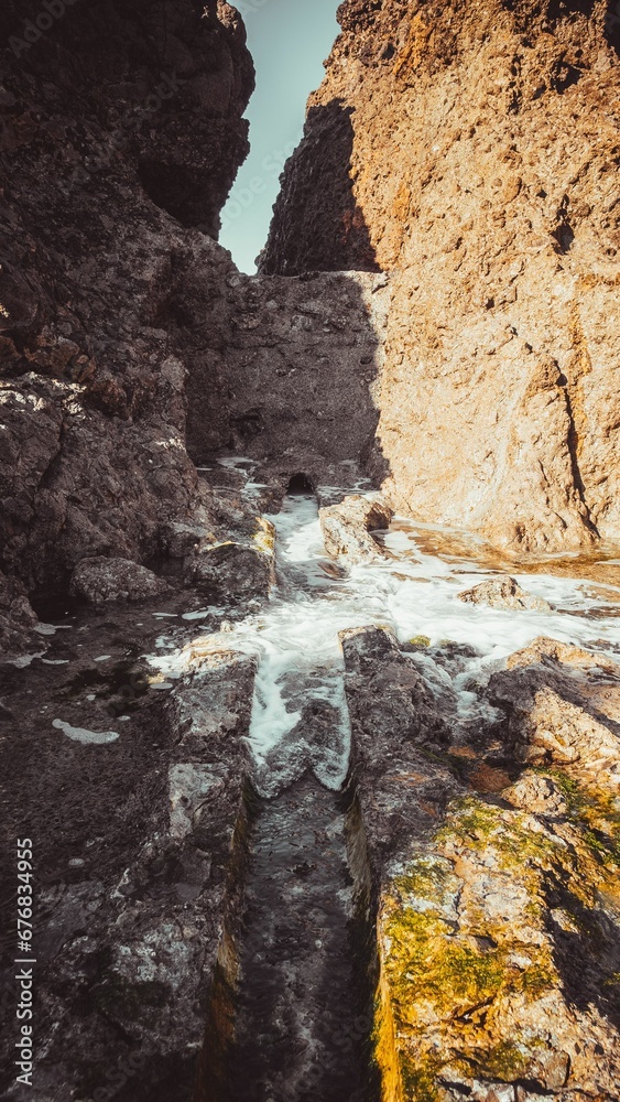 Vertical shot of water flowing through a carved hole in a rock