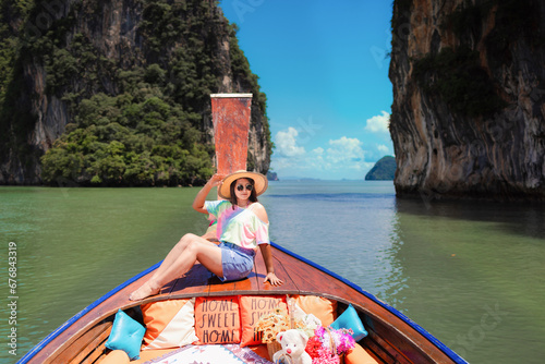 Traveler woman in summer dress relaxing on wooden boat joy view of Phang Nga bay, near Phuket, Travel in nature place Thailand,
