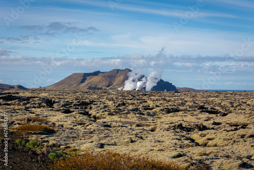 Volcanic landscape of Reykjanes peninsula with lava fields and gas steam of Svartsengi Geothermal Power Plant and Blue Lagoon, seen from road 43, Iceland. photo