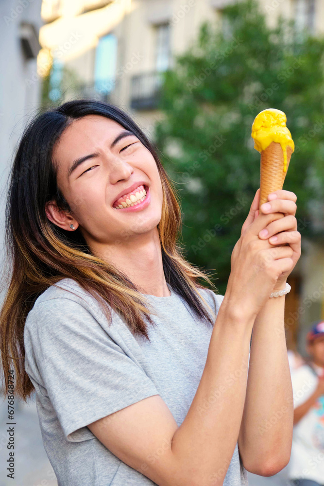 Taiwanese young man laughing with a mango ice cream in summer. Taiwanese young man laughing with a mango ice cream in summer.
