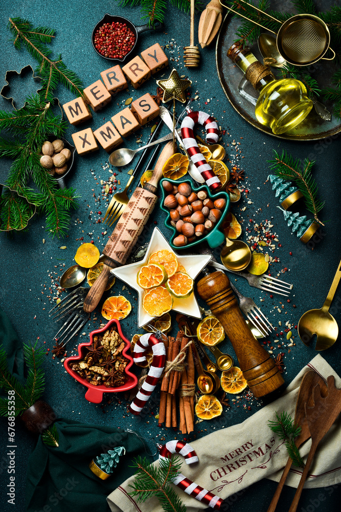 Christmas tree made of vintage kitchen stuff, spices, sweets and utensils. On a dark slate background. Top view.