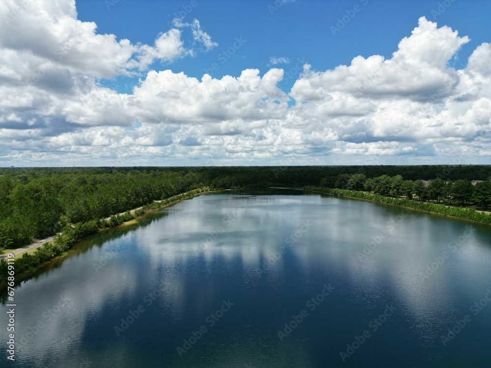 Beautiful view of a lake surrounded by trees under a blue cloudy sky.