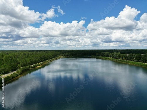 Beautiful view of a lake surrounded by trees under a blue cloudy sky.