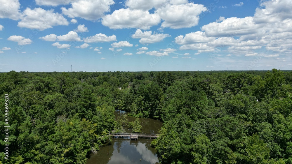Aerial view of the bridge over the river in a forest under a blue sky
