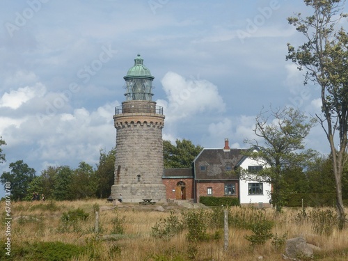 Hammeren Lighthouse on Bornholm island surrounded by vegetation and with a cloudscape in background