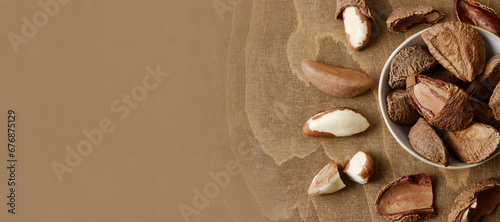 Unshelled and shelled Brazil nuts banner, brown table. Top view. photo