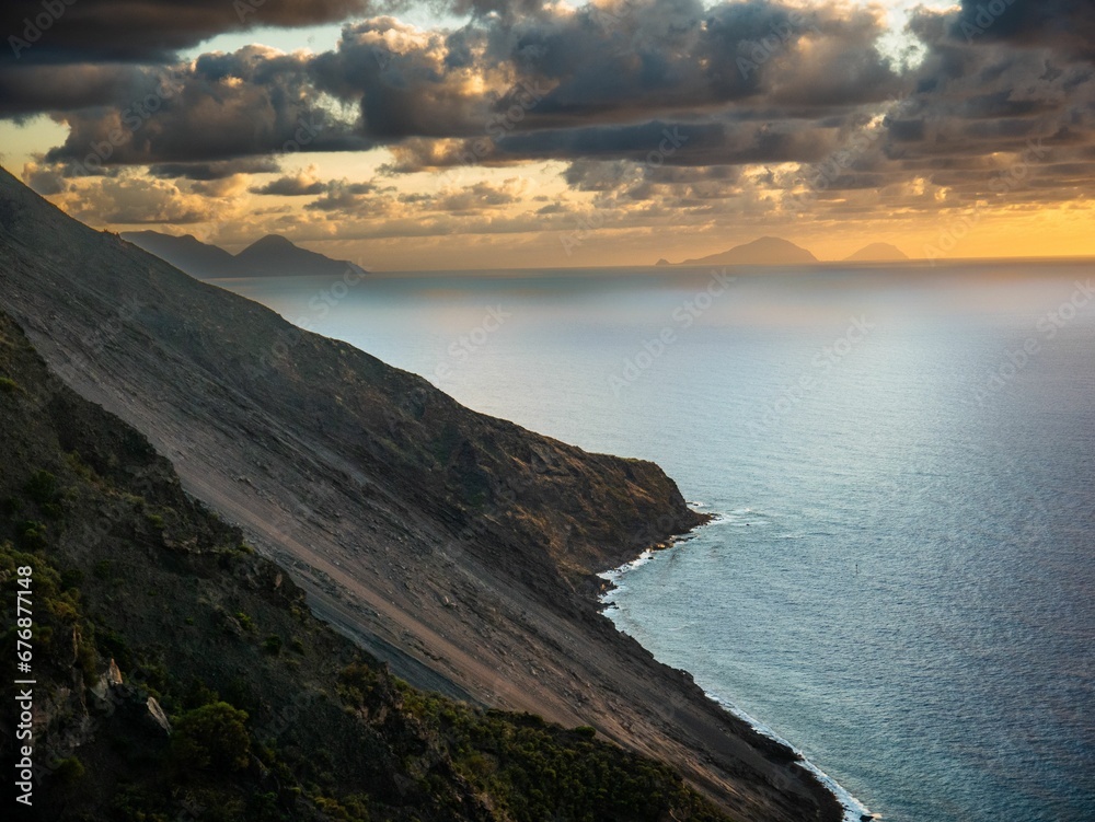 Beautiful shot of the Stromboli volcano and a sea under the bright cloudy sky Beautiful shot of the Stromboli volcano and a sea under the bright cloudy sky