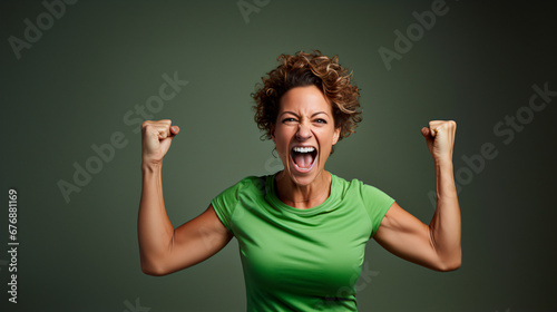 mujer de mediana edad mostrando músculos de brazos, fuerte, positiva, vestida de verde  photo